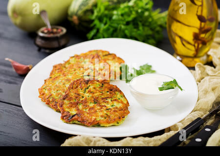 Zucchini pancakes with parsley on a wooden table. Stock Photo