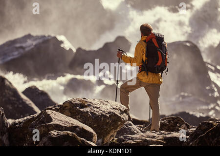 Hiker hiking with backpack looking at waterfall Stock Photo