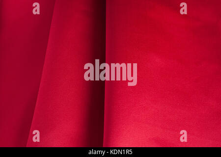 Folds of red silk fabric in dark tones. Stock Photo
