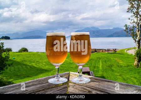 Two half-pint printed glasses of Belhaven beer on a table overlooking Loch Linnhe, Hollytree Hotel, Kentallen, Glencoe, Argyll and Bute, Scotland Stock Photo