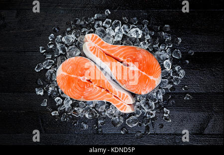 Salmon steak on ice on black wooden table top view Stock Photo