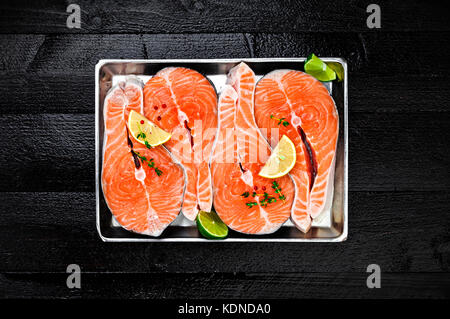 Salmon steaks on metal tray on black wooden table top view Stock Photo