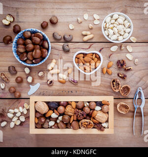 Different kinds of nuts walnuts kernels ,macadamia,hazel nuts, almond,chest nuts,cashew nuts and pistachio with nut and shell crackers on rustic woode Stock Photo