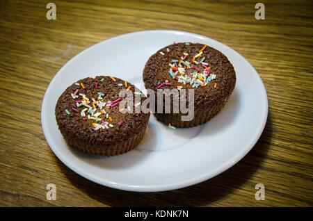 Two chocolate cakes with multi colored truffle, isolated on a white plate Stock Photo