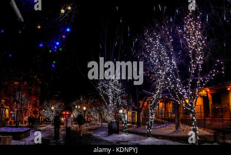 Night street in downtown Aspen, Colorado, decorated with Christmas lights and decorations; blurry figures of people walking along the street; USA Stock Photo