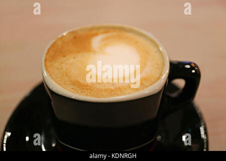 Closed up Heart Shaped Milk Foam of Cappuccino Coffee in a Black Cup, with Selective Focus Stock Photo