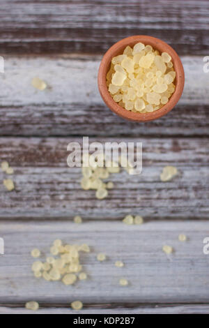 Mastic gum on clay bowl over rustic wooden background Stock Photo