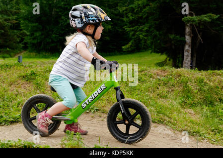 A three year old girl riding a balance bike Stock Photo