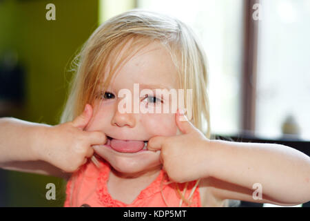 A three year old girl pulling faces Stock Photo