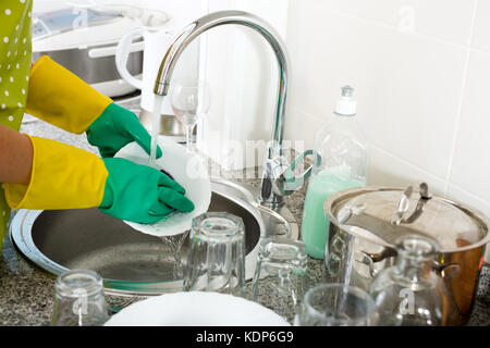 View on hands in protective rubber gloves making dishes in sink Stock Photo