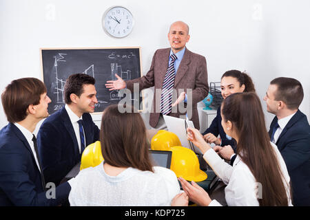 Team of successful creative engineers and architects discussing business project and smiling indoors Stock Photo