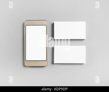 Blank business cards and smartphone on gray paper background. Objects for placing your design. Top view. Stock Photo