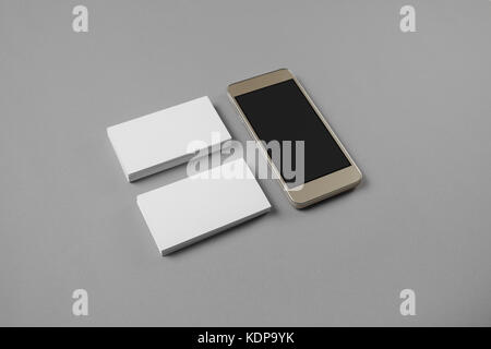 Smartphone and blank business cards on gray paper background. Template for branding identity. Stock Photo