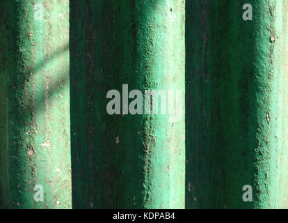 Sunlit green painted wavy slate background. Shabby wavy slate texture with unevenness and dust Stock Photo