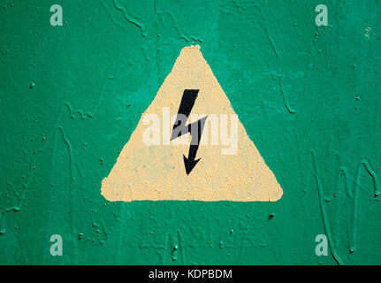 Yellow high voltage triangle warning sign on green metal wall Stock Photo