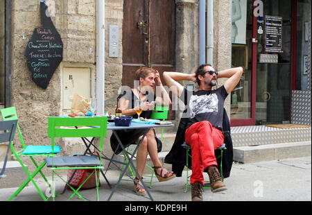 Man and woman hipster couple relaxing at a street cafe table in the Languedoc town of Pezenas, France Stock Photo