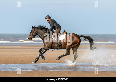 Southport, Merseyside, Sunny in Southport. 15th October 2017. UK Weather.  Greg Mook rides his 13 year old horse 'Monty' through the shallow tide on a gorgeous warm & sunny day at Southport in Merseyside.  Credit: Cernan Elias/Alamy Live News Stock Photo