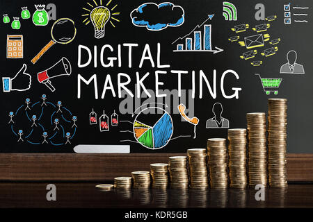 Stack Of Coins In Front Of Blackboard Showing Digital Marketing Concept Stock Photo