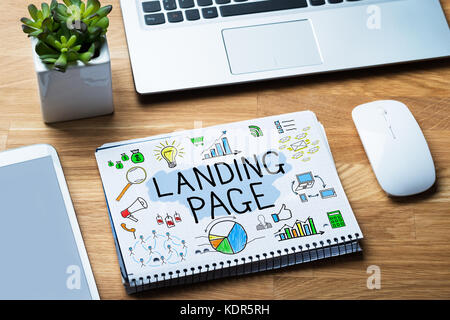 High Angle View Of Notepad Showing Landing Page Concept On Wooden Desk Stock Photo