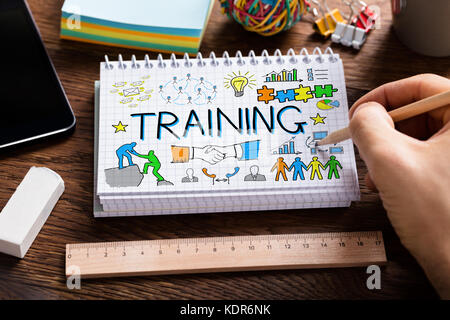 High Angle View Of Person Hand Holding Pencil Drawing Training Concept On Notepad At Wooden Desk Stock Photo