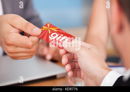 Close-up Of Person Hand Giving Gift Card To Another Person Stock Photo