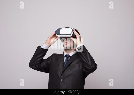 Young handsome businessman in black suit wearing virtual reality goggles., isolated on white background Stock Photo