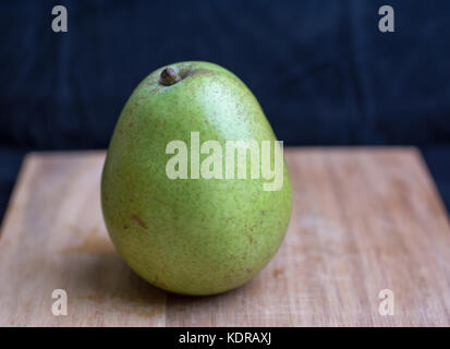 a single Bartlett green and red pear on a cutting board. Stock Photo