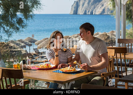 Young couple sitting in a cafe near the sea and eats a sweet dessert Stock Photo