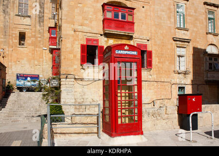 British style red telephone box in Battery Street, Valletta, Malta, overlooked by red balcony Stock Photo