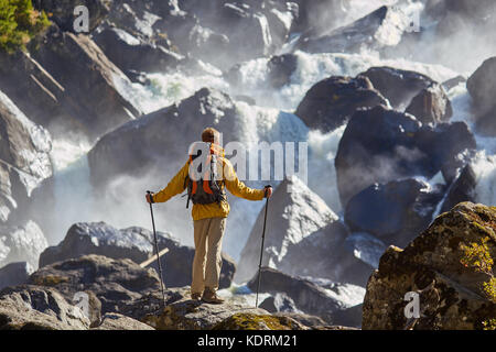 Hiker hiking with backpack looking at waterfall Stock Photo
