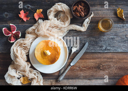 Pancakes with butter, pecan nuts, figs and honey on wooden table with copy space for text. Autumn food, pumpkin pancakes. Still life Stock Photo