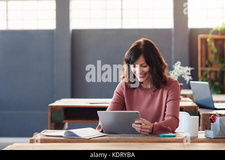 Young businesswoman sitting at her desk using a digital tablet Stock Photo