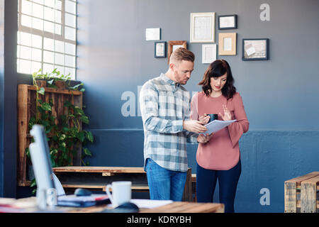 Two focused work colleagues discussing paperwork together in an office Stock Photo