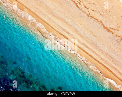 Top view of a deserted beach. The greek coast of the Ionian Sea. Aerial photo of sea waves reaching shore. Stock Photo