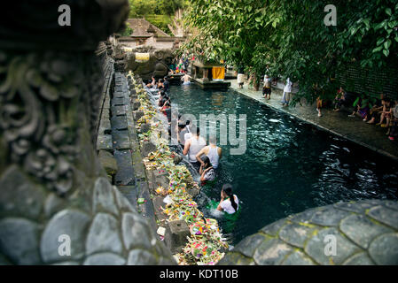 Bali, Indonesia - July 06, 2017. People praying at Holy water temple and in the water. Stock Photo