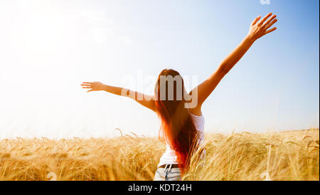 Girl with raised hands on wheat field Stock Photo