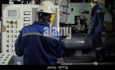 Two workers in production plant as team discussing, industrial scene in background. two worker in factory on the machine. Worker with out safety equipment caught in the machine Stock Photo