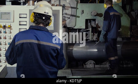 Two workers in production plant as team discussing, industrial scene in background. two worker in factory on the machine. Worker with out safety equipment caught in the machine Stock Photo