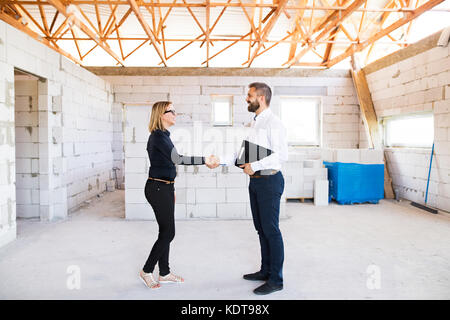 Architect and civil engineer shaking hands at the construction site. Stock Photo