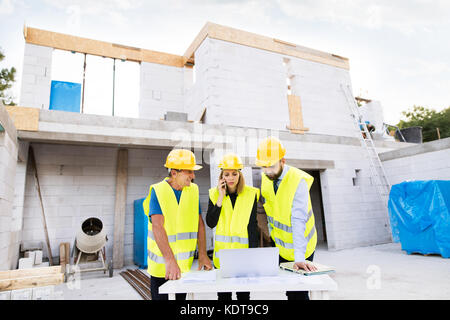 Architect, civil engineer and worker with a laptop and smartphone, discussing issues at the construction site. Stock Photo