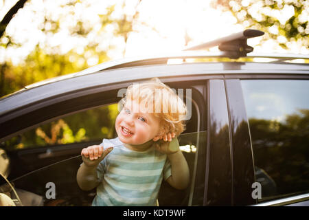 Cute little boy playing in the car, looking out of the window. Stock Photo