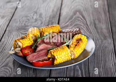 Blue clay plate with slices of mildly fried steak and corn Stock Photo