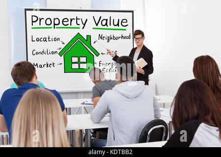 A Male Teacher Explaining The Concept Of  Property Value Concept To Students In Classroom Stock Photo