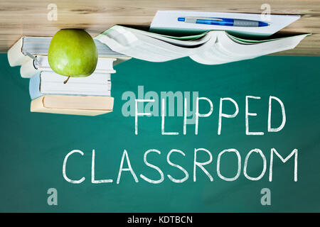 Flipped Classroom Concept On Blackboard With Stacked Book And Apple On Wooden Table Stock Photo