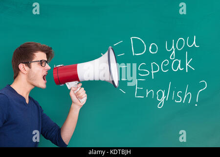 Young Man Doing Announcement Of English Speaking Using Megaphone On Blackboard Stock Photo