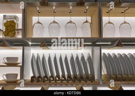 wooden shelves with wine glasses, plates, cups and can of noodles closeup in the dining area Stock Photo