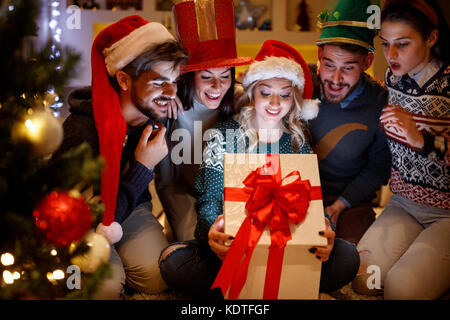 happy smiling friends opening magic Christmas gift Stock Photo