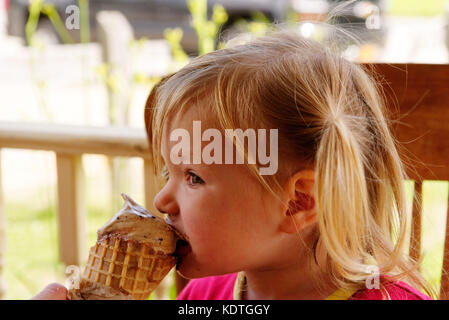 A little girl (3 yrs old) eating a chocolate ice cream