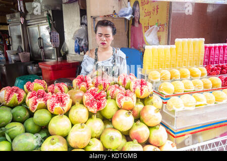 Street food vendor selling fresh orange and pomegranate juice from a mobile food cart, Chinatown, Bangkok, Thailand Stock Photo