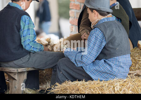 Asti, Italy - September 10, 2017: Children dressed in vintage clothes play cards on a bale of hay Stock Photo